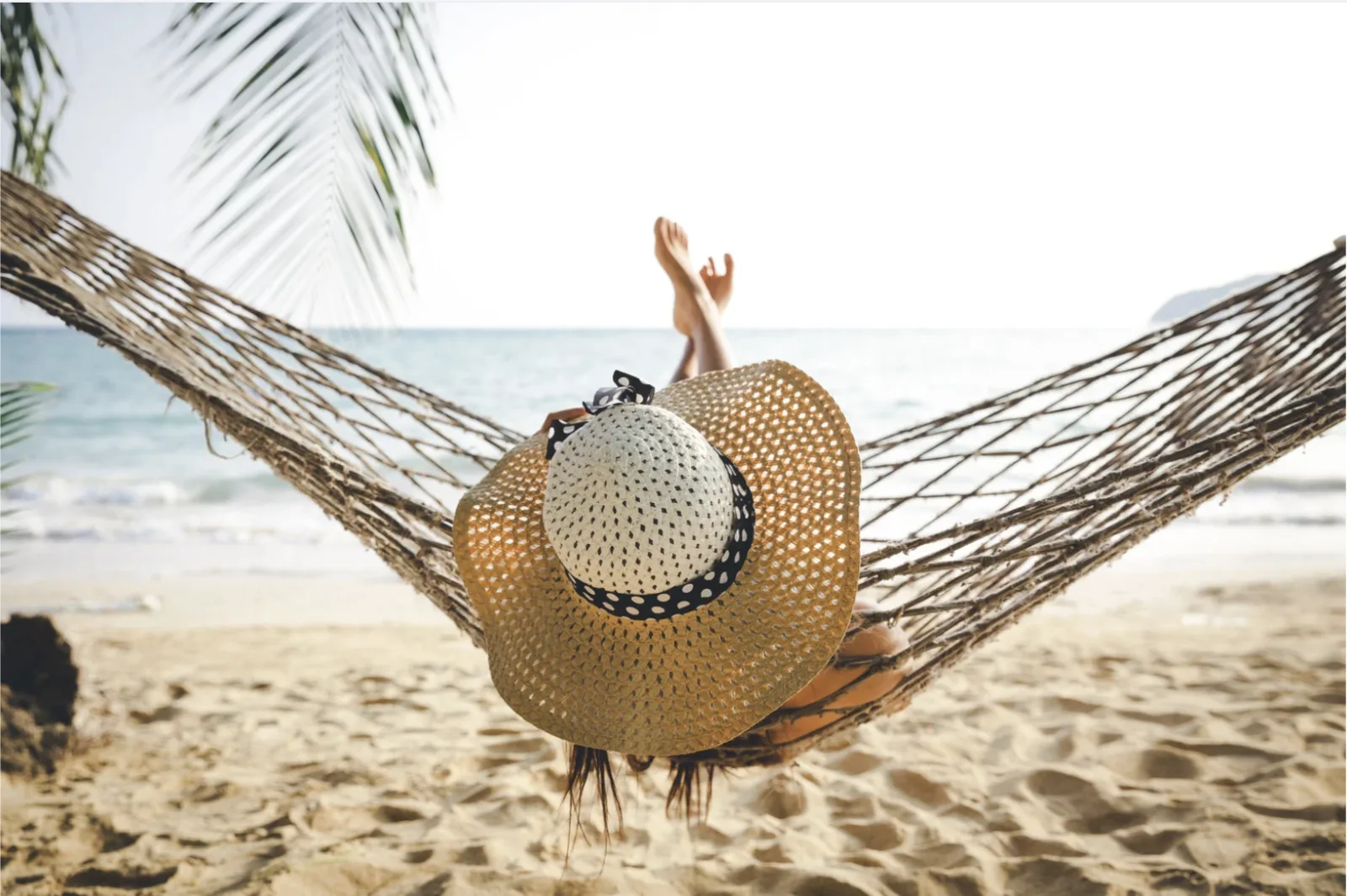 A traveller resting in a hammock facing the sea