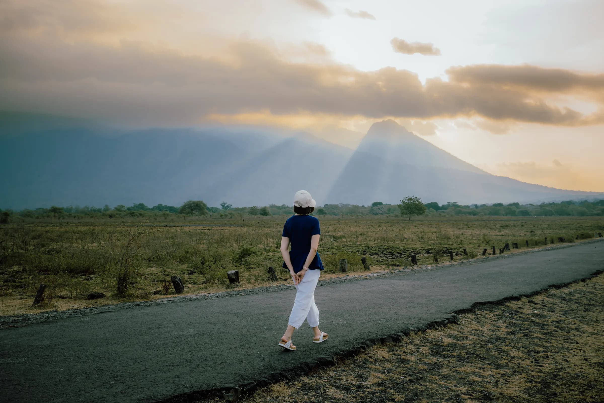 Savanna road at Baluran with sun rays breaking over the volcano