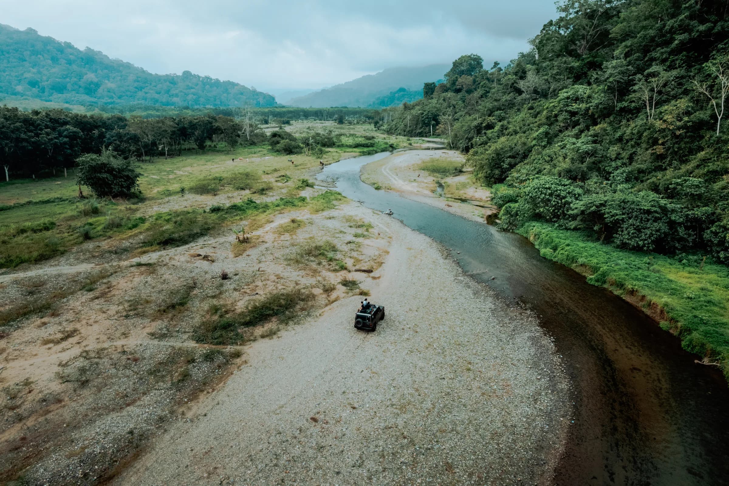 Aerial of a jeep crossing the river valley into Meru Betiri's jungle